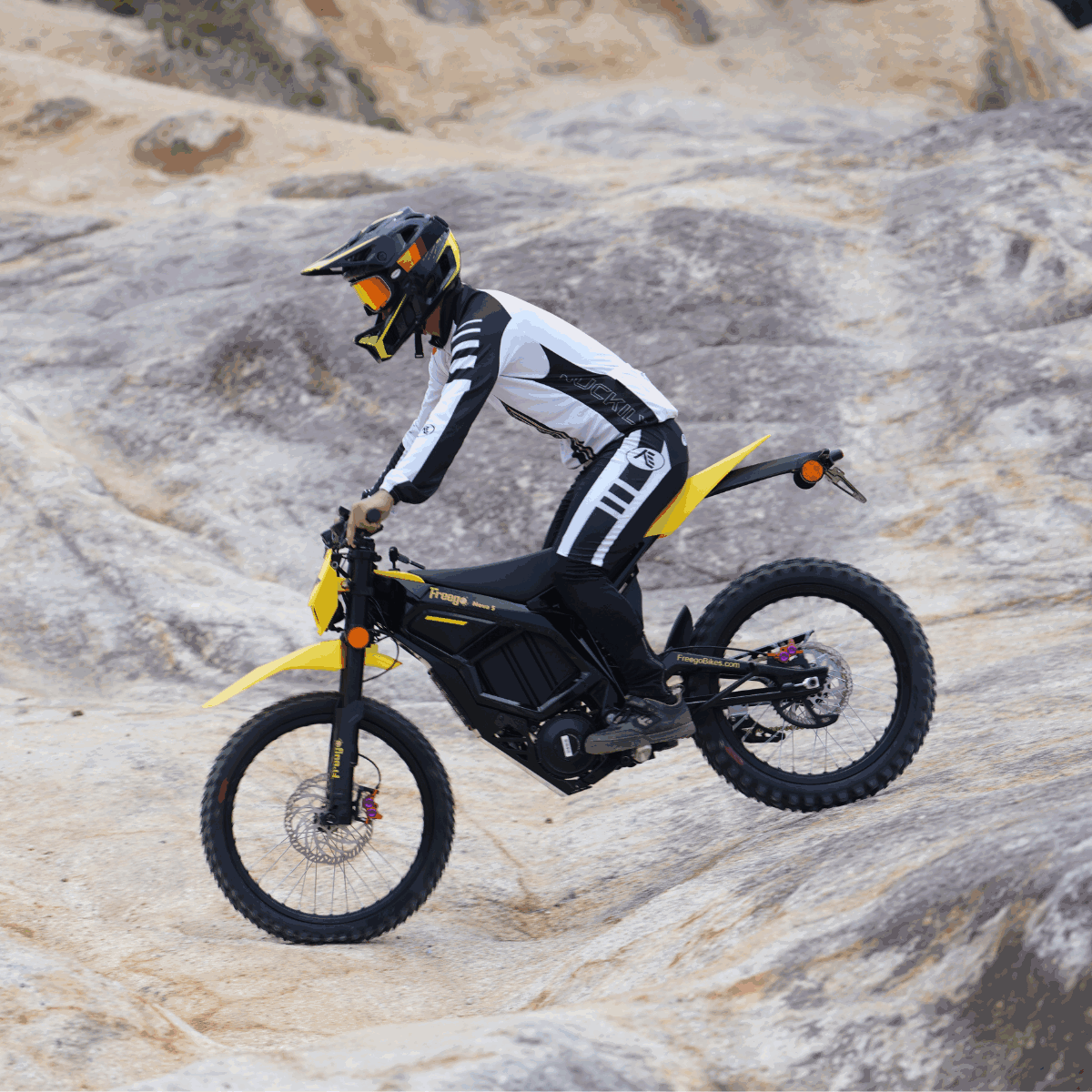 Rider on Freego Nova 5 electric dirt bike navigating rocky uphill terrain.