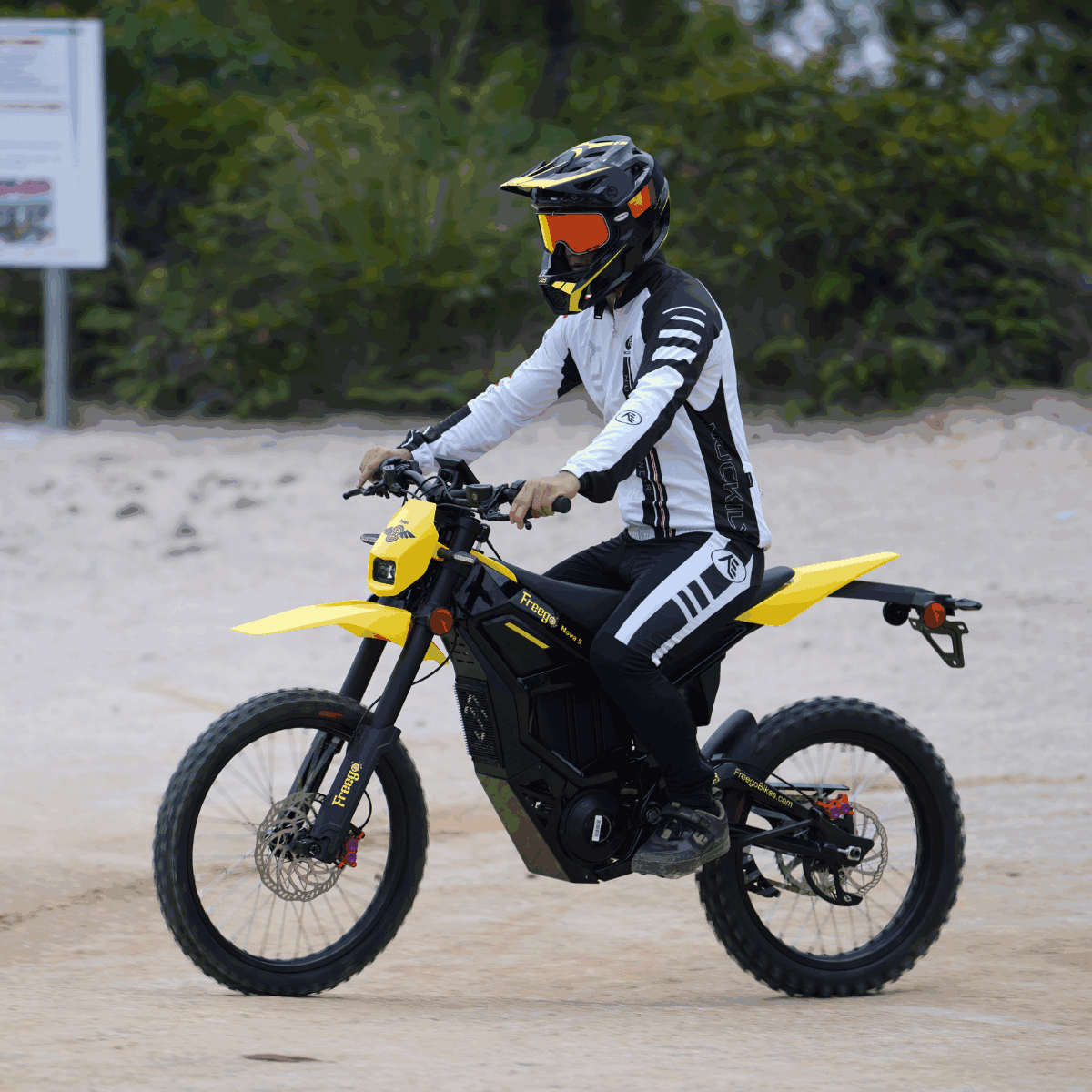 Rider on Freego Nova 5 electric dirt bike wearing full gear on a sandy trail