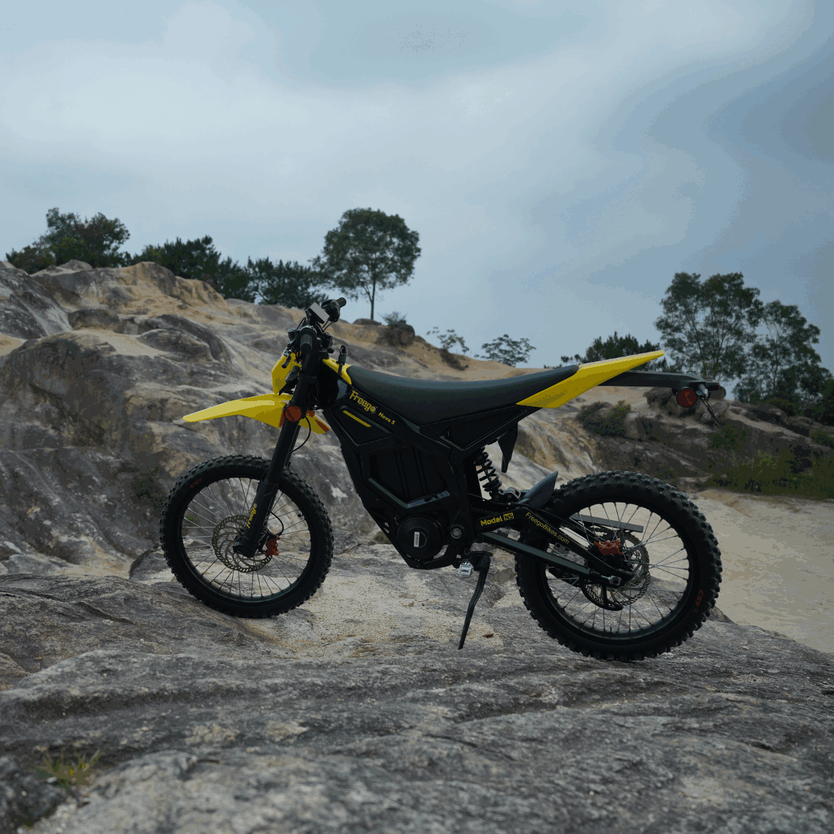 Freego Nova 5 electric dirt bike parked on rocky terrain under a cloudy sky