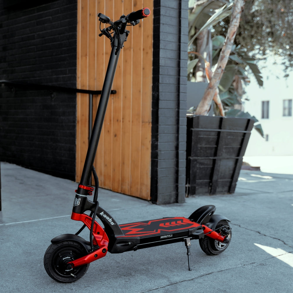 Kaabo Mantis 8 Lite electric scooter in red and black color parked outdoors, showing sturdy frame and wide tires for city commuting.