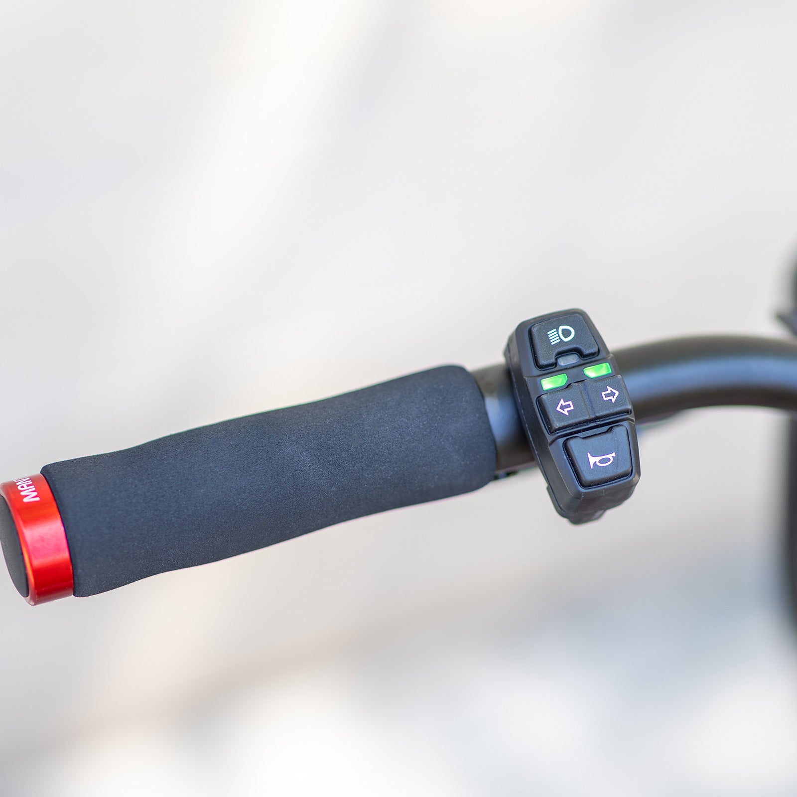 Close-up of the Kaabo Mantis 8 Lite handlebar switch controls, showing light, horn, and turn signal buttons for easy operation.